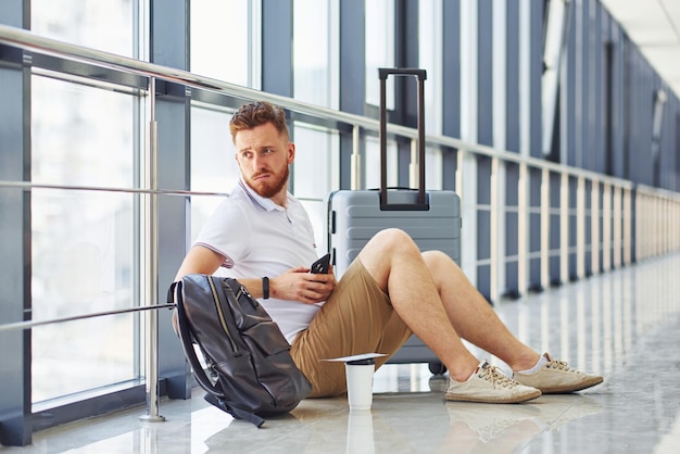 Man is on the ground young traveler is on the entrance hall in\
the airport