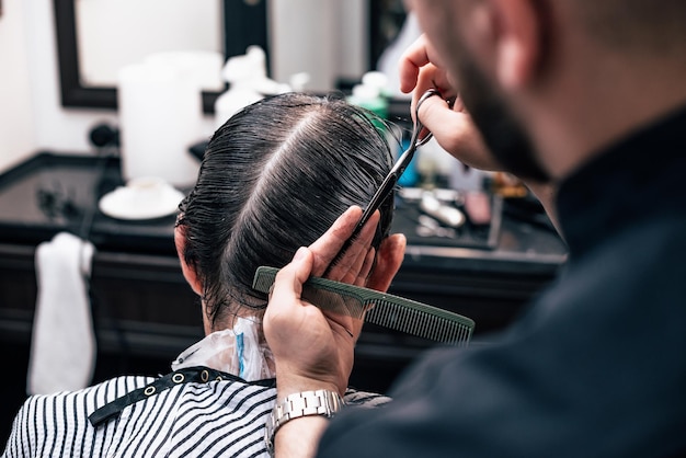 男が美容院でぶらぶらしている。理髪店でのヘアカットとスタイリング。ひげと髪の男性のケア。