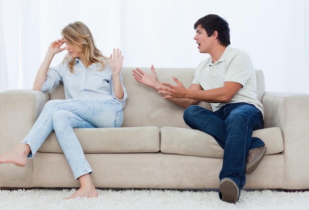 남자는 소파에 앉아있는 동안 그의 여자 친구와 논쟁을하고있다