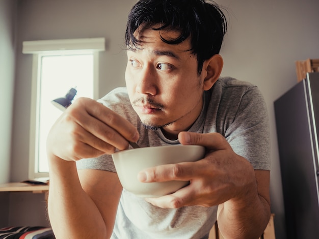 남자는 아침 식사로 지루한 시리얼을 먹고 있습니다.