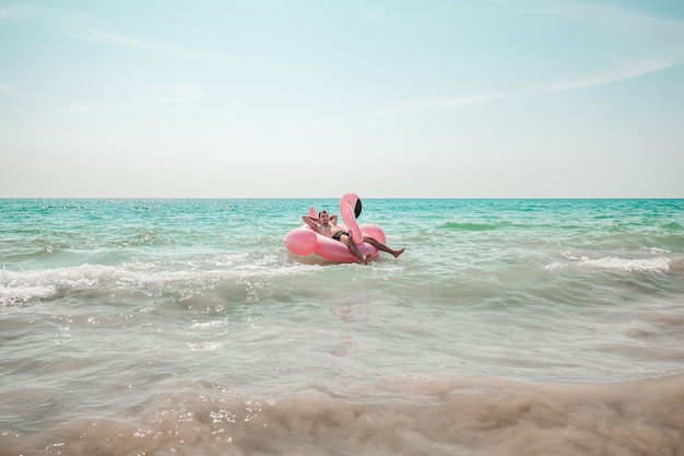 Man is having fun on pink flamingo inflatable pool float