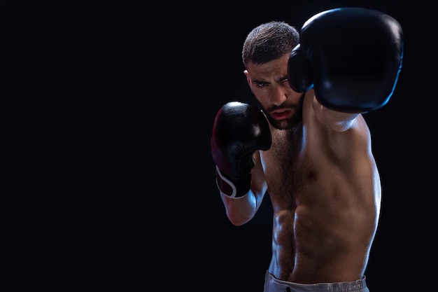 Man is hitting an opponent focused fighter with naked torso and boxing gloves looking at the camera win