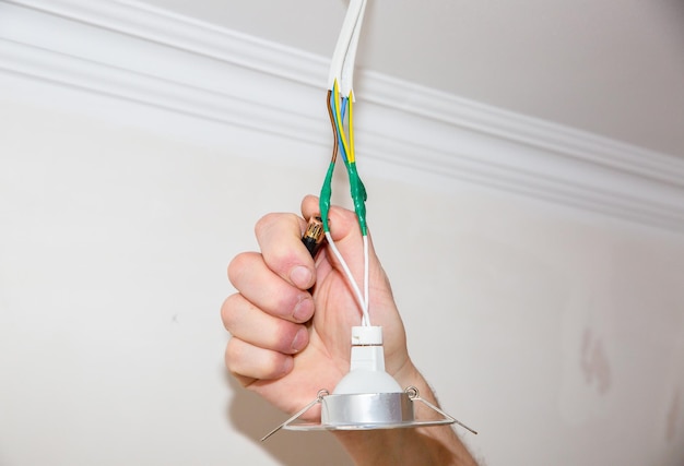 Man is holding adhesive tape in his hands Electrical insulator for light bulb Maintenance repair works in the flat Restoration indoors