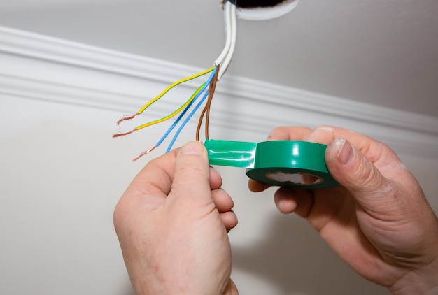 Man is holding adhesive tape in his hands electrical insulator
for light bulb maintenance repair works in the flat restoration
indoors