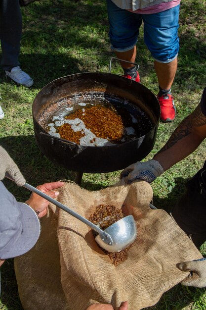 大きな鍋を背景に食べ物の入った袋を持っている男性。