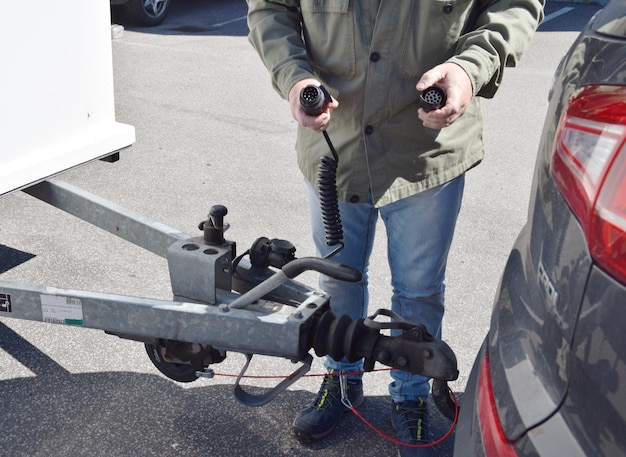 A man is holding a car hitch that is attached to a vehicle.