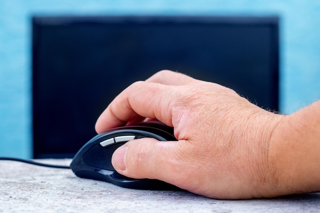 A man is holding a computer mouse near the computer