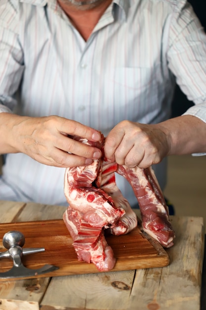 The man is holding and cutting pork ribs