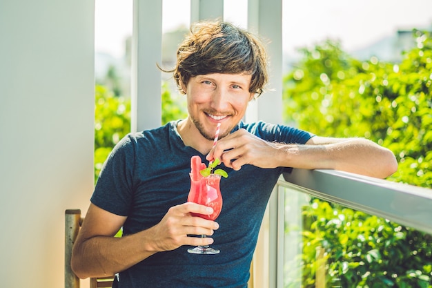 Man is holding Healthy watermelon smoothie with mint and striped straw