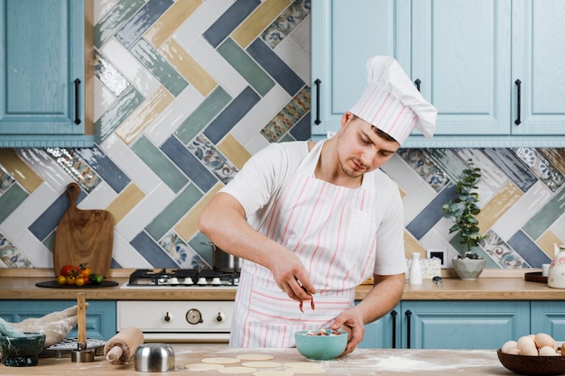 A man is holding a khinkali in close-up. Cook in the kitchen. The process of preparing a national dish.