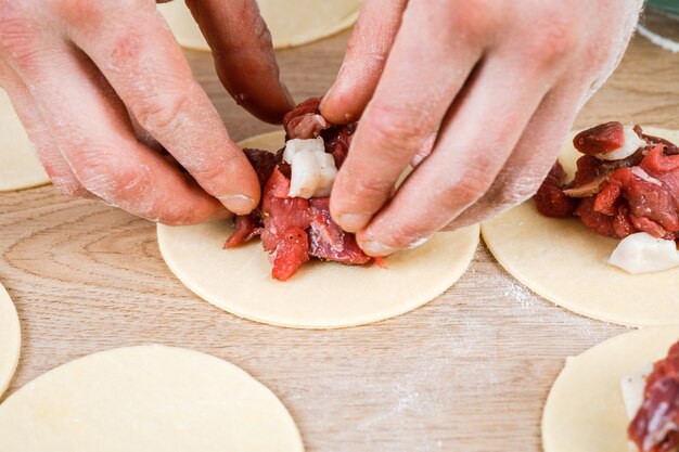 A man is holding a khinkali in close-up. Cook in the kitchen. The process of preparing a national dish.