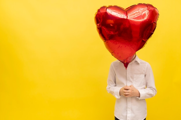 man is holding large balloon in the shape of heart. Happy valentine's day greetings.