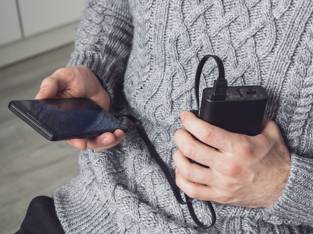 A man is holding a phone and a power bank