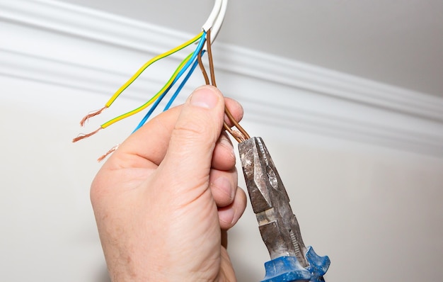 Man is holding pliers in his hands Electrical insulator for light bulb Adhesive tape for maintenance repair works in the flat Restoration indoors