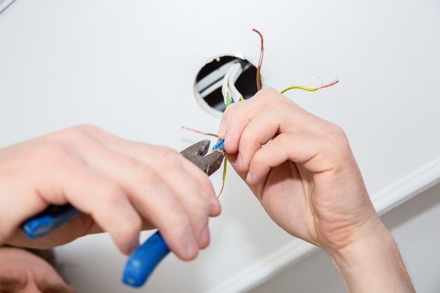 Man is holding pliers in his hands Electrical insulator for light bulb Adhesive tape for maintenance repair works in the flat Restoration indoors