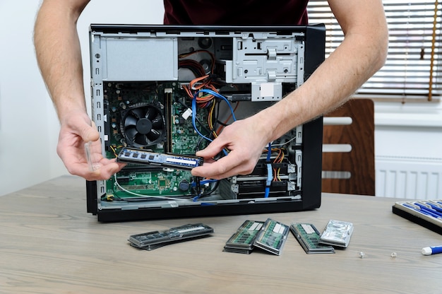 A man is holding a RAM slot to upgrade of the computer.