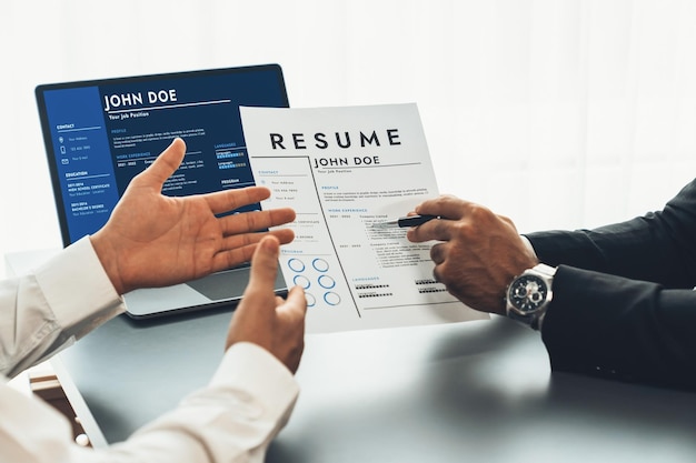 Photo a man is holding a resume and a computer monitor is in the background.