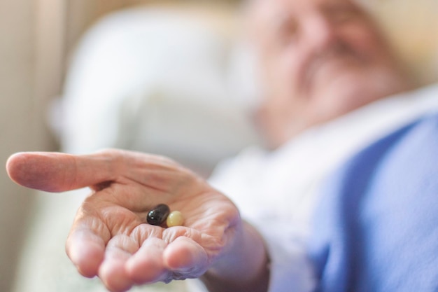 A man is holding two pills in his hand.