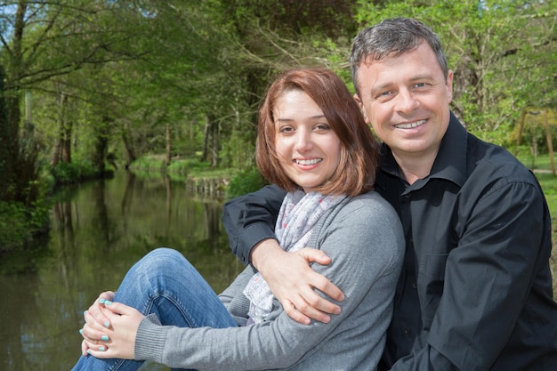 Man is hugging his girl friend by the river