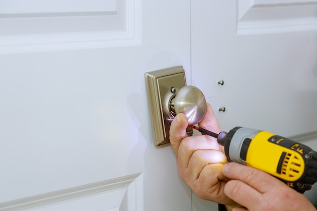 The man is installing the new dummy lock of the door by the screwdriver