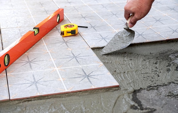 A man is laying a floor with a trowel and a tape measure.