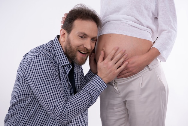 Man is Listening Pregnant Belly of His Woman