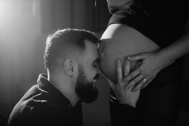 A man is looking at a pregnant woman's belly.