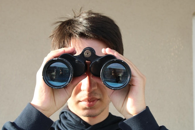 A man is looking through a pair of binoculars.