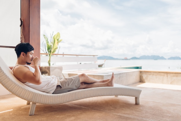 L'uomo è sdraiato sulla panchina sentendosi rilassarsi con la vista sul mare durante la sua vacanza.