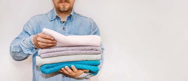 Man is organizing and cleaning the house a stack of clean terry towels in hand concept