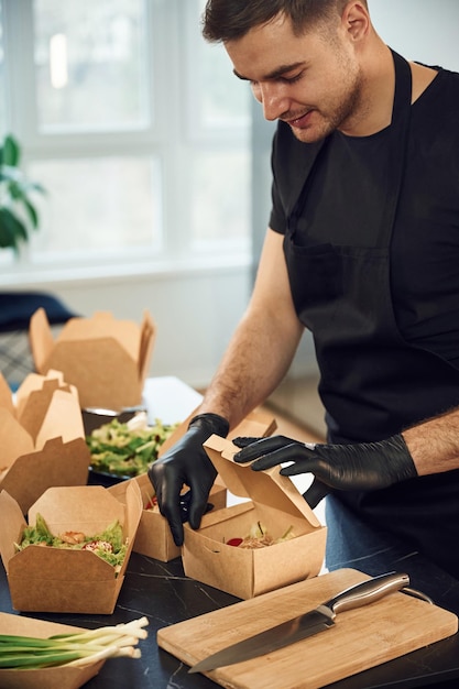 Человек упаковывает еду в бумажные эко-коробки в ресторане.