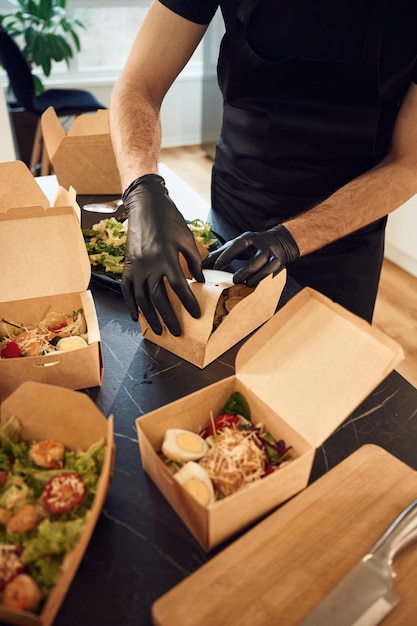 Man is packing food into the paper eco boxes Indoors restaurant