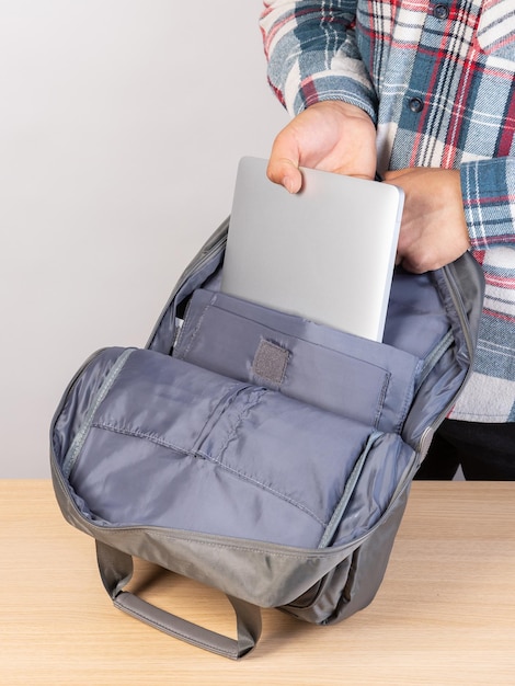 A man is packing his laptop into a backpack closeup