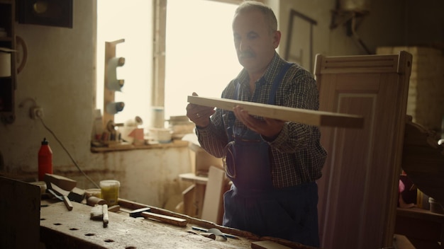 Photo a man is painting a piece of wood with a hammer.