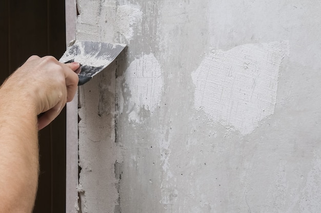 Photo man is plastering the walls in the room. close-up.