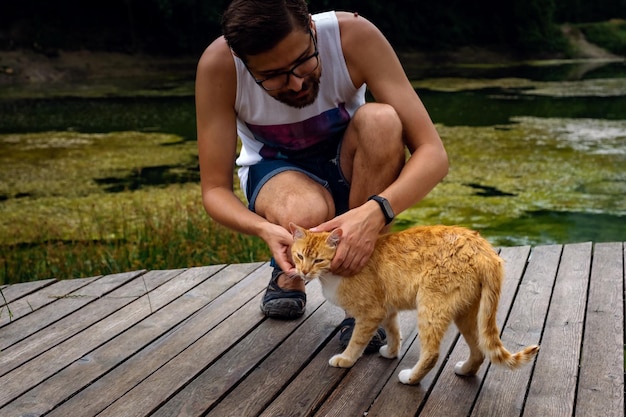 Мужчина играет с домашней рыжей полосатой кошкой