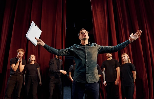 L'uomo sta esercitando il suo ruolo gruppo di attori in abiti scuri durante le prove a teatro