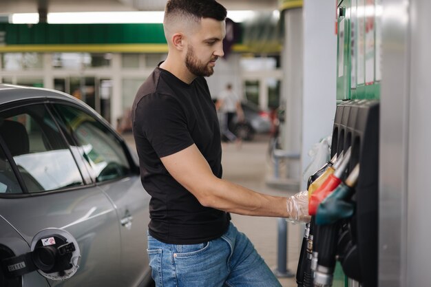 Man is preparing for refueling at gas station male hand filling benzine gasoline fuel in car petrol