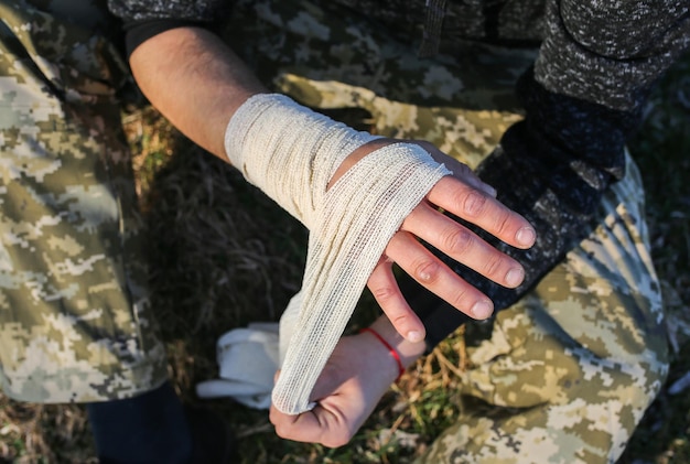 남자가 삔 손목에 붕대를 감고 있다. 뒤틀린 팔. 자연 속에서 부상당한 관광객. 등산.