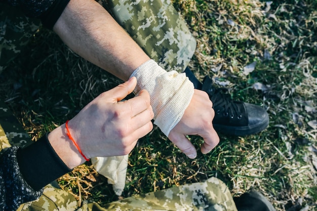 Man is putting bandage on sprained wrist Twisted arm Injured tourist in the nature Hiking