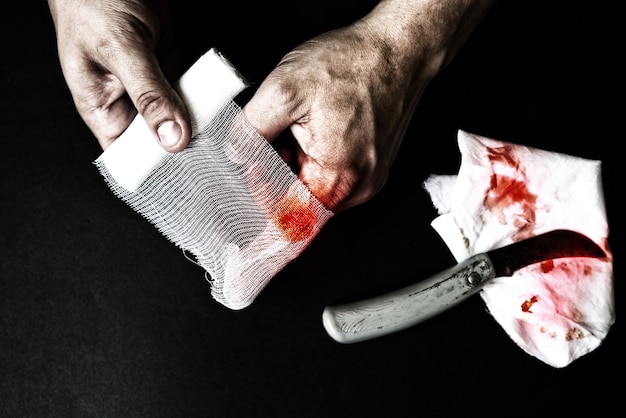 Мужчина накладывает повязку на рану. Кровоточащая травма. Глубокий надрез ножом.