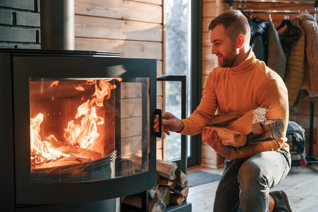 写真 男は家の屋内の暖炉に薪を入れている