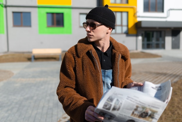 A man is reading the news on the newspaper in the street