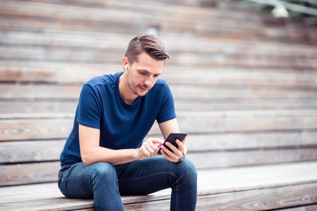 Man is reading text message on mobile phone while walking in the park