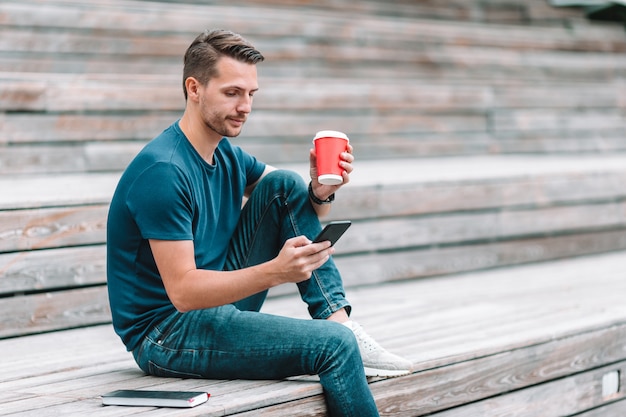 남자는 공원에서 산책하는 동안 휴대 전화에서 문자 메시지를 읽고 있습니다
