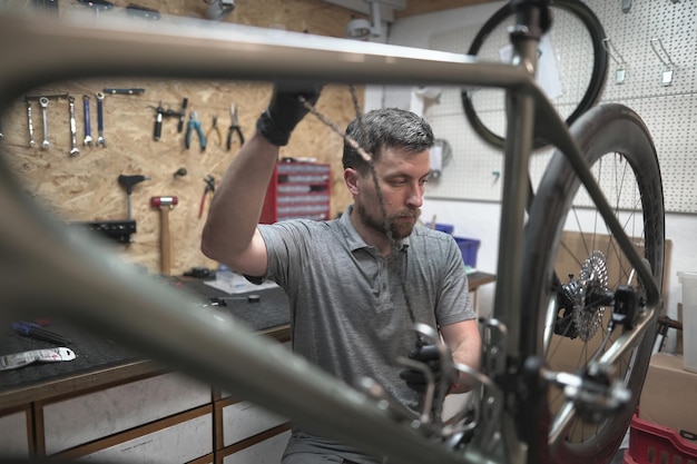 男性が自転車のタイヤ車輪フォーク車輪輪のに作業するガレージで自転車を修理しています