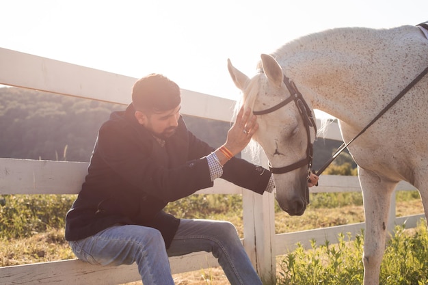 男は牧場で馬と一緒に休んでいます