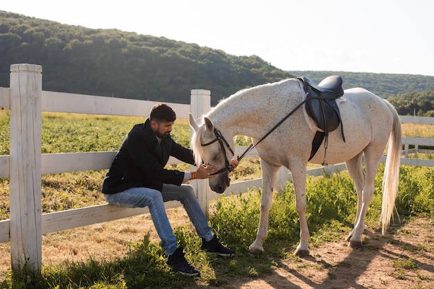 The man is resting with a horse on a ranch