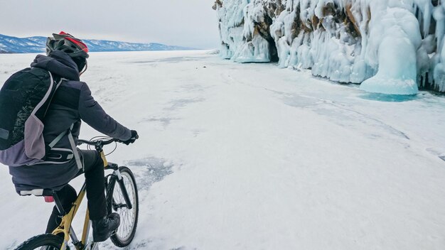 Мужчина едет на велосипеде возле ледяного грота Скалы с ледяными пещерами