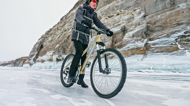Man is riding bicycle near ice grotto rock with ice caves\
icicl